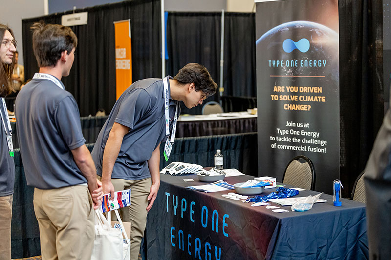 people reviewing type one energy booth at trade show photo