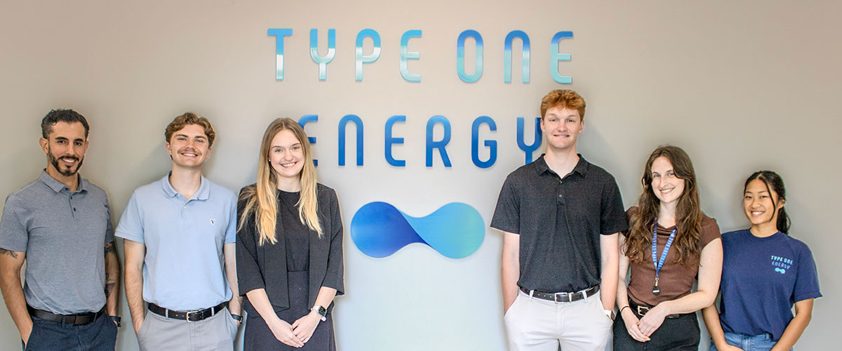 Type One Energy interns posing in front of logo sign photo